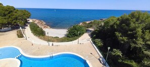 A pool area with a view of the sea, surrounded by trees and a white fence. - Impressive penthouse on the seafront (PEÑISCOLA)