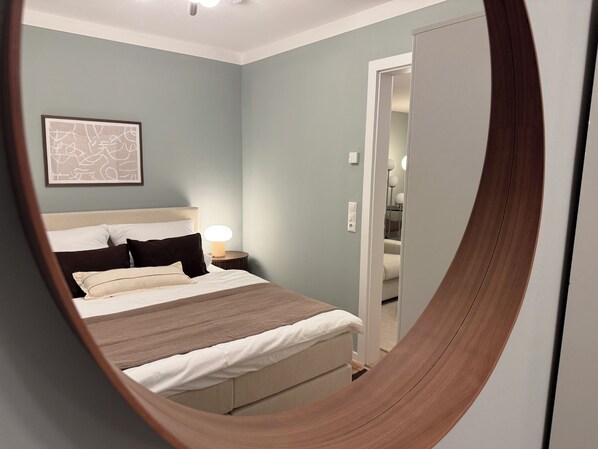 Un dormitorio con cama, lámpara de noche y un cuadro en la pared.