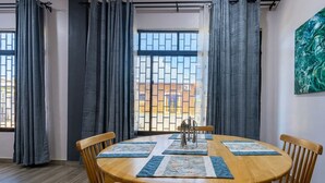 A dining area with a round wooden table, four chairs, and a window with metal bars.