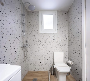 Un baño con ducha, inodoro y ventana.