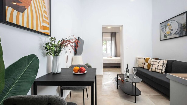 Una sala de estar moderna con una mesa de comedor, sofá y obras de arte en las paredes.