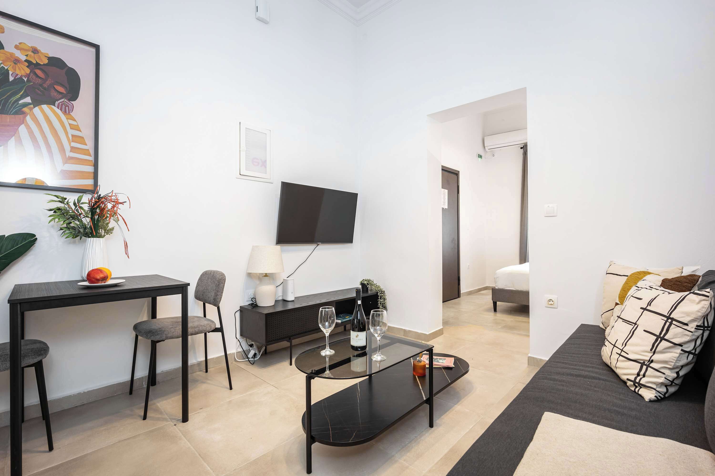 A modern living room with a flat-screen TV, a dining table, and a sofa.