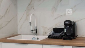 Una cocina con un lavamanos blanco, una cafetera Bosch y un salpicadero de mármol.