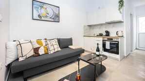 Una sala de estar moderna con un sofá, una mesa de centro y una zona de cocina con estufa y armarios.