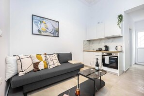 Uma sala de estar moderna com sofá, mesa de centro e área de cozinha com fogão e armários.