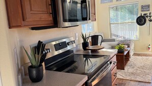 A kitchen with wooden cabinets, stainless steel appliances, and a countertop with a plant.