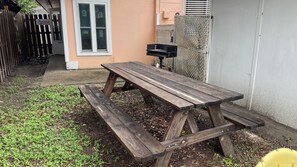A wooden picnic table with benches in a backyard. - Charming Efficiency Unit w/Cool AC in Aransas Pass (Aransas Pass)