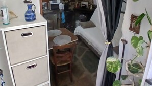 Ein gemütliches Zimmer mit Steinwand, einem Esstisch mit Stühlen, einem weißen Schrank und einem schwarzen Vorhang.