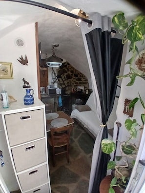 A cozy room with a stone wall, a dining table with chairs, a white cabinet, and a black curtain. - Bisinchi village (village Bisinchi)
