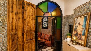 Un interior tradicional amb una porta de fusta, una finestra de vitrall, un mur amb dibuixos i un sofà.