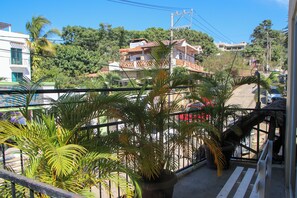 Un balcón con plantas en macetas, vistas a una zona residencial y cielo despejado.