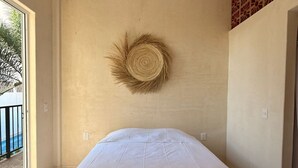 Un dormitorio con cama, ventilador de techo, un adorno en la pared y vistas al exterior.