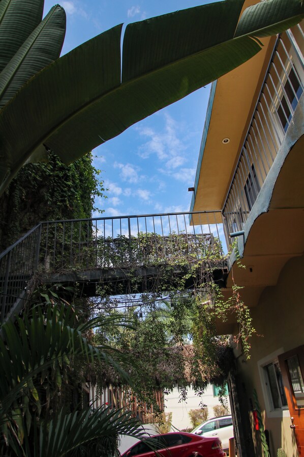 Un edificio con balcón, un puente y un coche estacionado frente a él.