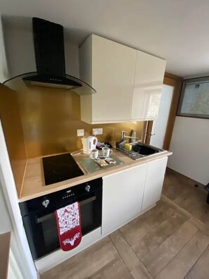 A compact kitchen with a stove, oven, and a single sink.