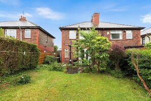 A residential area with two brick houses, a small garden with a pond, and a hedge. - Spacious Home with Garden for Groups & Families (Greater Manchester)