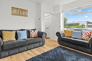 Ein modernes Wohnzimmer mit zwei grauen Sofas, einem blauen Teppich und einem Bild an der Wand.