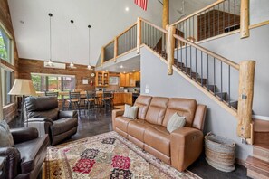 A spacious living area with a leather sofa, a dining table, and a staircase.