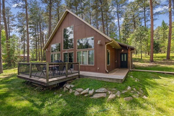 A cabin with a deck, large windows, and a door.