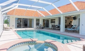 Ein überdachter Pool mit gefliestem Dach, Liegestühlen und einer Terrassenfläche.