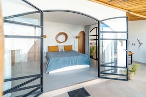 Ein modernes Schlafzimmer mit einem Bett, einer runden Holzwanddekoration und Blick ins Freie.