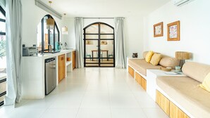 A modern living room with a sofa, a dining area, and a kitchen. - 5 Villas | 5 Private Pools | Tamarindo | 14 Guests (Tamarindo)