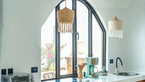 A kitchen with a large window, a coffee machine, a toaster, and hanging macramé lights. - 5 Villas | 5 Private Pools | Tamarindo | 14 Guests (Tamarindo)