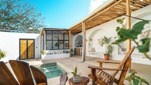 A modern outdoor patio with a pool, wooden furniture, and potted plants. - 5 Villas | 5 Private Pools | Tamarindo | 14 Guests (Tamarindo)