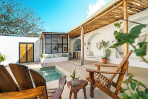 Eine moderne Außenpatio mit Pool, Holzmöbeln und Topfpflanzen.