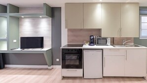 A compact kitchen with a built-in oven, microwave, and dishwasher, a flat-screen TV, and a small countertop. - Quiet duplex ground floor - Center Puy - GR65 stage (Le Puy)