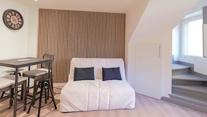 A modern room with a bed, a dining table with chairs, a wall clock, and a window. - Quiet duplex ground floor - Center Puy - GR65 stage (Le Puy)