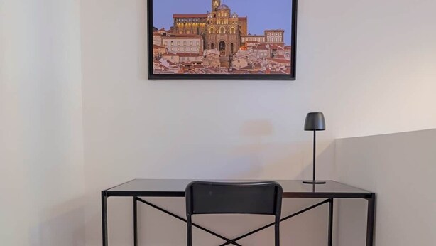 A framed cityscape artwork on a wall, a desk with a chair, and a floor lamp. - Quiet duplex ground floor - Center Puy - GR65 stage (Le Puy)
