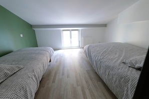 Una habitació amb dos llits, una finestra i un radiador.