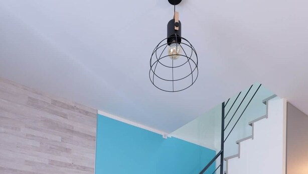A modern living room with a white desk, a TV on a wooden stand, a staircase, and a blue accent wall. - GR65 Compostelle stage - Duplex 5 pers -Center Puy (Le Puy)