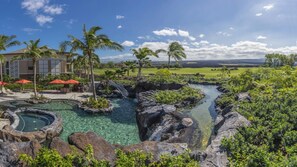 A resort with a pool, palm trees, and a view of the landscape.