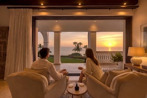 Ein Paar sitzt auf einem Balkon mit Blick auf den Sonnenuntergang über dem Meer.