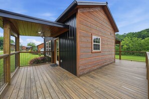 Une cabane en bois dotée d’une terrasse couverte et offrant une vue sur un paysage verdoyant.