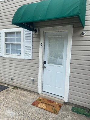 A house with a white door, a green awning, and a doormat. - Nice 2 Bedroom/3 Beds/1.5 Bath Apartment - Bryant3 (Bryant)