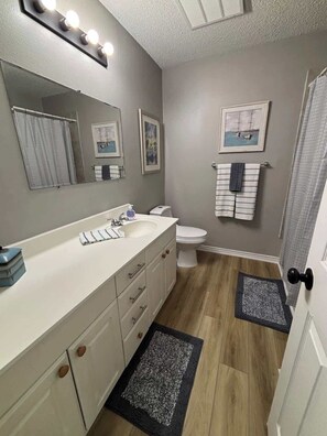 Een badkamer met een wastafel, wasbak, spiegel en toilet.