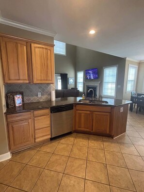 A kitchen with wooden cabinets, a dishwasher, a built-in oven, and a large island with a sink. - Condo Townhome - F4 - 3 Bedrooms - Hot Springs (Garland County)