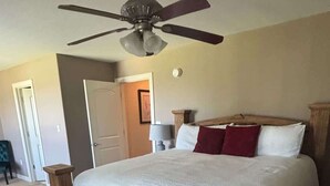 Une chambre à coucher avec un cadre de lit en bois, un ventilateur de plafond et un sol recouvert de moquette.