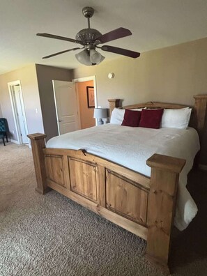 A bedroom with a wooden bed frame, a ceiling fan, and a carpeted floor. - Two Adjacent Condos - Perfect for Large Families! (Garland County)