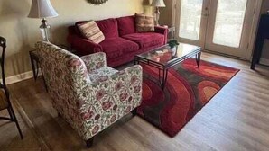 Un salon avec un canapé rouge, un fauteuil à motifs et une table basse.