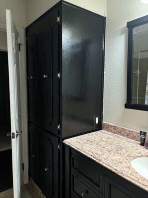 Un baño con un mueble negro, una encimera de granito y un espejo.