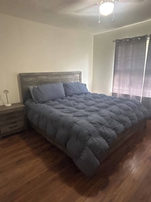 Ein Schlafzimmer mit Bett, Holzboden und Nachttisch.