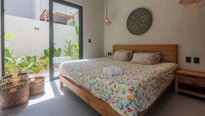 Une chambre à coucher avec un lit, une tête de lit en bois, une assiette décorative accrochée au mur et des paniers en osier.