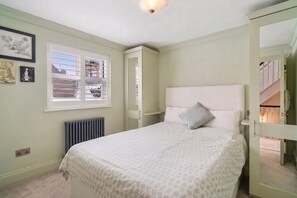 A bedroom with a bed, a window, a radiator, and a wardrobe. - Luxury Kensington Townhouse near Hyde Park (London)