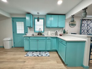 A kitchen with teal cabinets, a white countertop, a sink, and a patterned rug. - Hidden Oasis- 2 bdrm 2 bath home (Port O'Connor)
