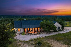 Ein Haus mit dunklem Dach, einer Veranda mit Sitzgelegenheit und Blick auf die Landschaft.