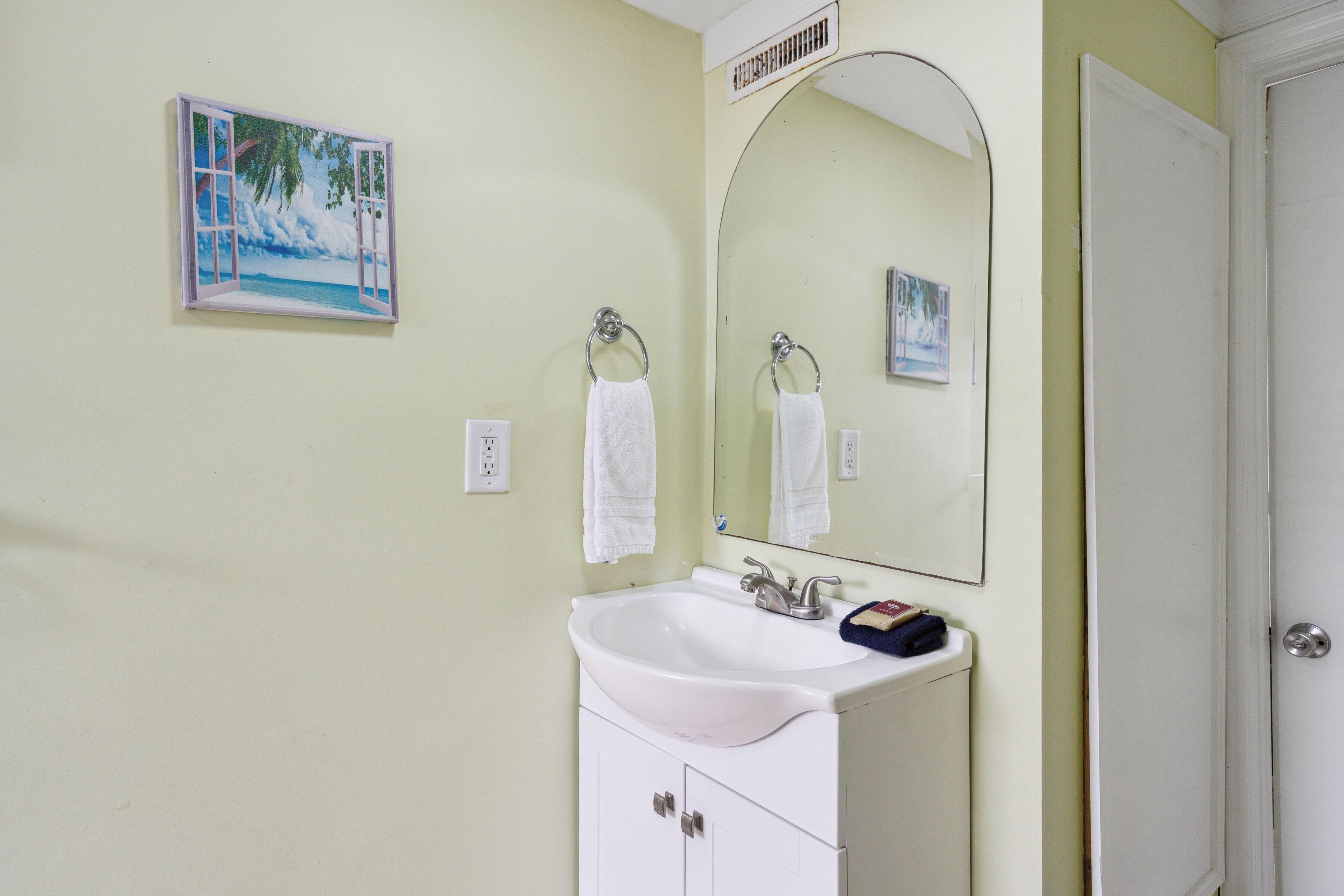 A bathroom with a white sink, a mirror, and a towel rack.