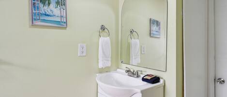 A bathroom with a white sink, a mirror, and a towel rack.
